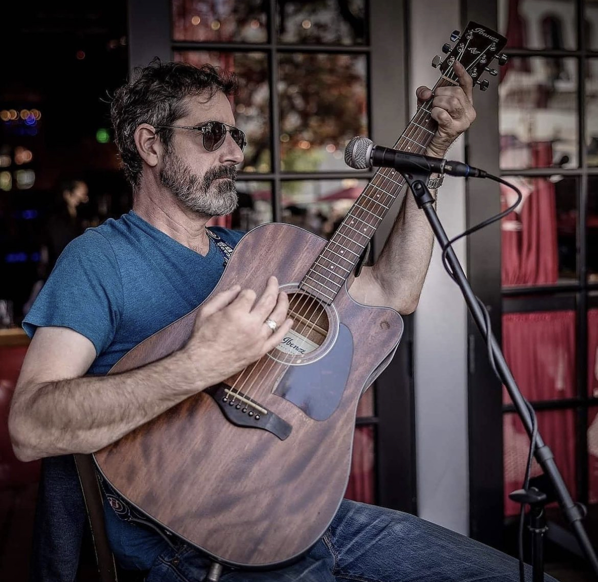 Man with sunglasses playing an acoustic guitar.